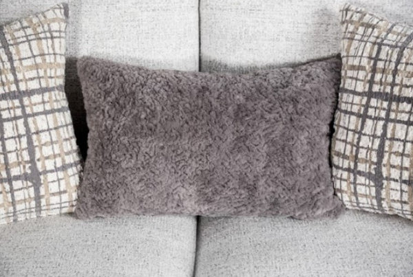 Gray textured pillow on a sofa with plaid-patterned pillows
