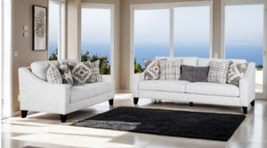 Mercia Sloped Track Arm Sofa Two white sofas with patterned cushions in a room with large windows.