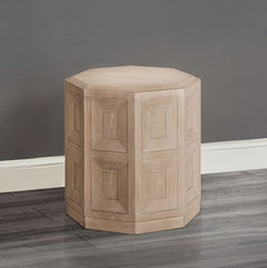 Montague Cross Modern Style Tawny End Table A light natural wood octagonal side stool with a paneled geometric design, shown on a dark gray wood floor against a gray wall.