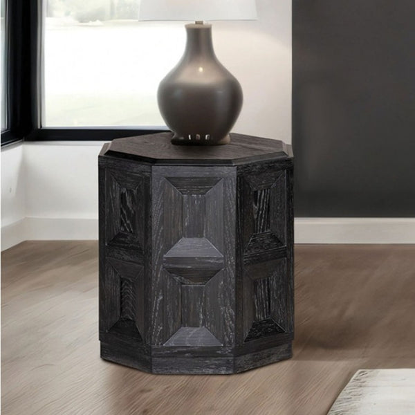 Montague Cross Modern Style Weathered Black End Table Hexagonal side table with textured surface and lamp on top in a room setting.