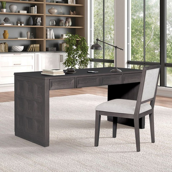 Montague Cross Modern Style Black Writing Desk A dark gray wooden writing desk with three drawers and a paneled front leg, paired with a matching gray upholstered chair, set in a bright home office with a bookshelf and large windows.