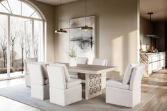 Montague Cross Modern Style Rectangular Dining Table A modern dining room featuring a rectangular light wood dining table surrounded by six upholstered dining chairs in a light beige fabric, set on a gray area rug. The room has warm beige walls, a large arched window looking out onto bare winter trees, and a contemporary abstract painting on the wall.
