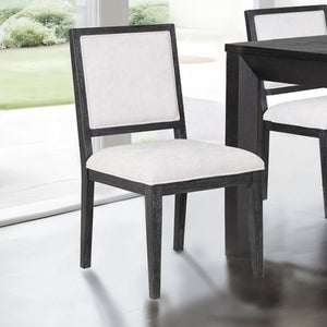 Montague Cross Modern Style Weathered Black Dining Chair Dining chair with white cushioned seat and backrest in a room with a table and window.