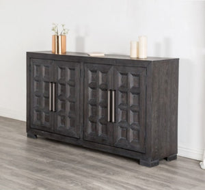 Montague Cross Modern Style Weathered Black Dining Server A dark charcoal gray wooden sideboard cabinet with four decorative paneled doors and vertical metal handles, styled in a room with gray wood flooring and a white wall.