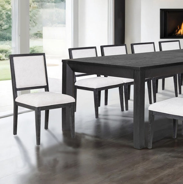 Montague Cross Modern Style Weathered Black Rectangular Dining Table A dark wood dining table with six matching chairs featuring dark frames and light beige upholstered seats, set in a modern dining room with a fireplace and large windows.