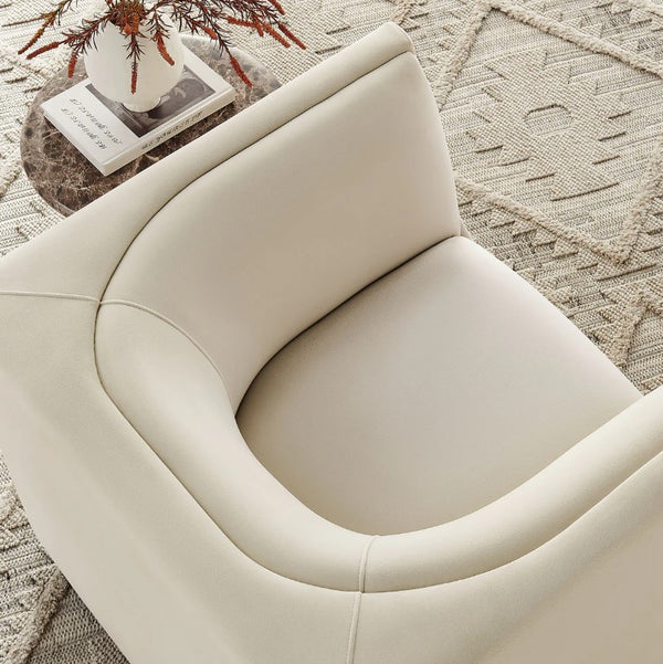 Natalia Alabaster Velvet Fabric Chair Beige armchair on a textured rug with a small table and decorative items.
