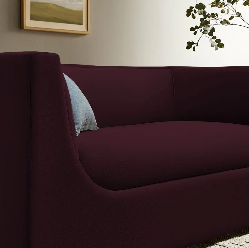 Natalia Mulberry Velvet Fabric Loveseat Maroon sofa in a living room with a painting and lamp in the background