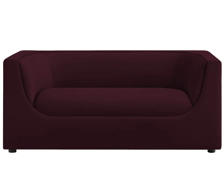 Natalia Mulberry Velvet Fabric Loveseat Maroon sofa in a living room with a painting and lamp in the background