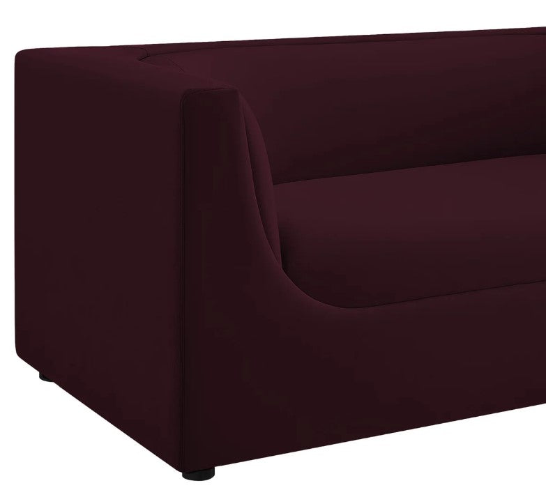 Natalia Mulberry Velvet Fabric Loveseat Maroon sofa in a living room with a painting and lamp in the background