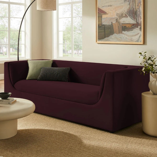 Natalia Mulberry Velvet Fabric Sofa Maroon sofa in a living room with a painting on the wall and a lamp.