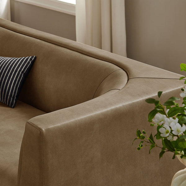 Natalia Premium Vegan Leather Sofa Brown leather sofa with a striped pillow and a vase of flowers in a room.