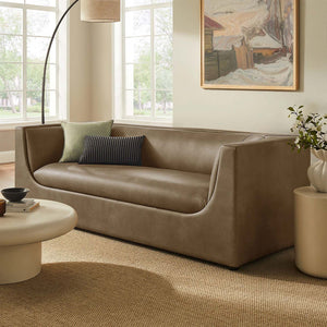 Natalia Premium Vegan Leather Sofa Beige sofa in a living room with a painting on the wall and a lamp.