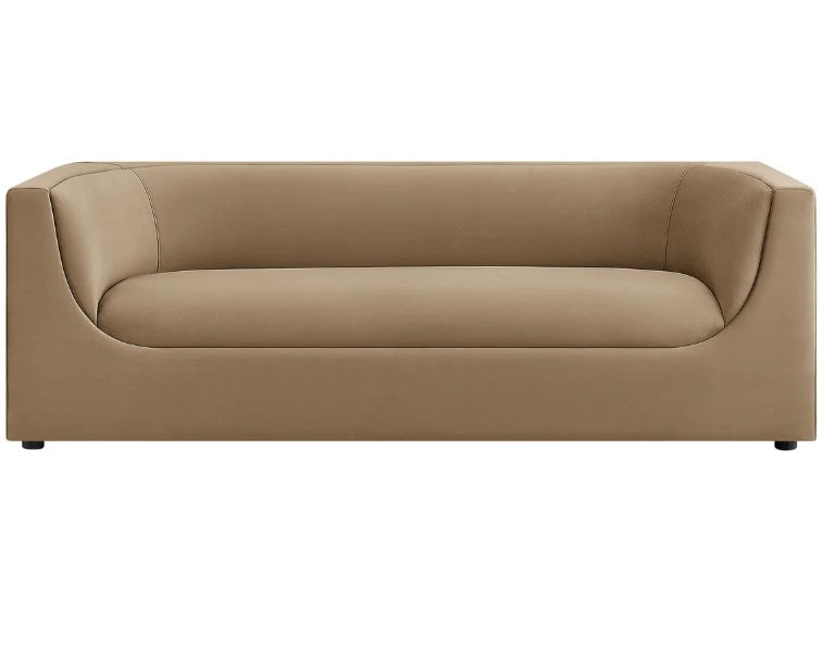 Natalia Taupe Velvet Fabric Sofa Beige sofa in a living room with a painting on the wall and a plant on a side table.
