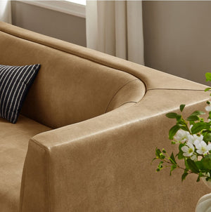 Natalia Toast Premium Vegan Leather Sofa Brown sofa with a striped pillow and a plant in a room with neutral decor.