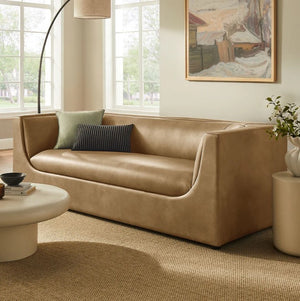 Natalia Toast Premium Vegan Leather Sofa Beige sofa in a living room with a painting on the wall and a plant on a side table.