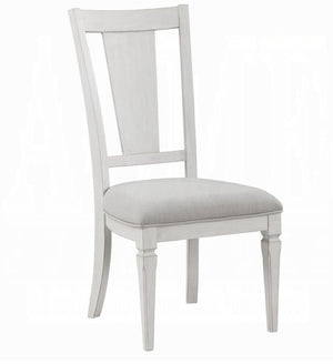 A light gray upholstered dining chair with a distressed white painted frame, featuring a tall slatted backrest and four tapered legs.
