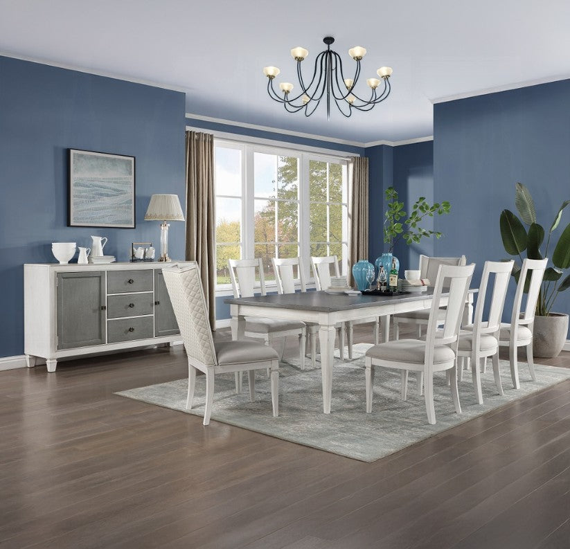 A white dining room set including a rectangular table, ten chairs, and a matching sideboard, staged in a dining room with blue walls, wood floors, and a window.