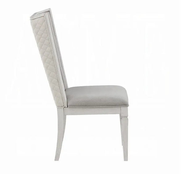 A light gray upholstered dining chair with a tall, diamond-quilted backrest and tapered legs, shown from a side profile on a white background.