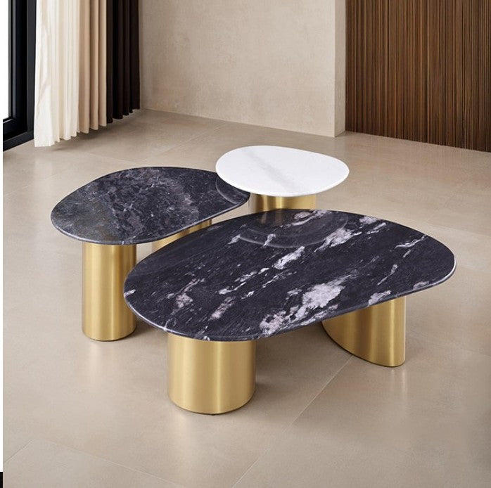 Naynem Coffee Table Oval Sintered Stone Black White Gold Finish An oval coffee table with a dark black and white marble top and two cylindrical gold metal legs, set on a light beige tiled floor.