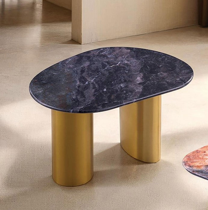 Naynem End Table Oval Sintered Stone Black Gray Gold Finish An oval side table with a dark purple marbled top and two cylindrical gold metal legs, set on a beige textured floor.