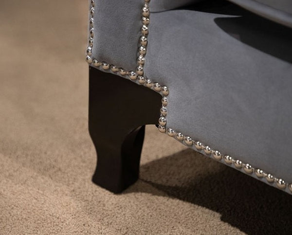 Nikki Gray Button Tufted Sofa Gray upholstered chair with railhead trim on a beige carpet