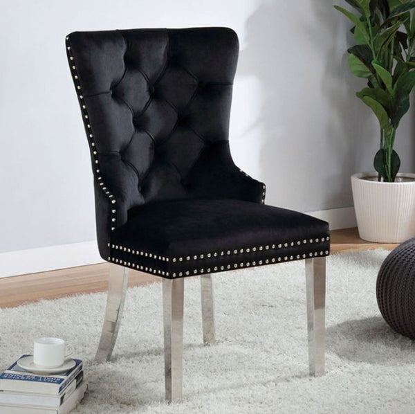 Noonwit Chrome Black Flannelette Fabric Chair (2/PK) A black tufted velvet dining chair with silver nailhead trim and tapered silver metal legs, shown in a styled room setting on a white rug with a potted plant and books in the background.