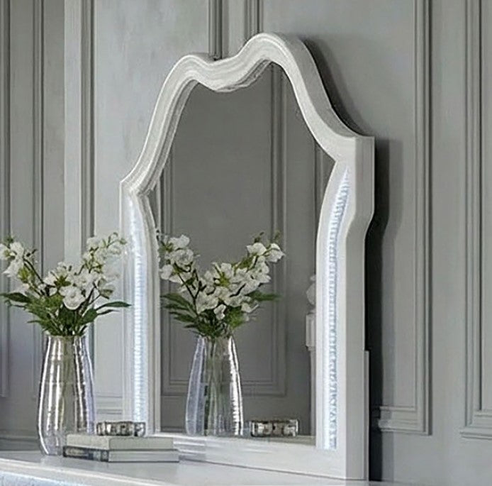Octavia Victorian Style Pearl White Mirror Decorative mirror with white frame on a gray wall with two clear vases holding white flowers.