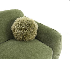 Green cushion with a fluffy texture on a green sofa against a white background