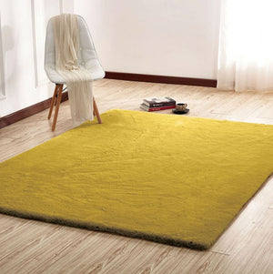 Patricia Power Loomed Modern Area Rug Yellow rug on a wooden floor with a chair and books in the background