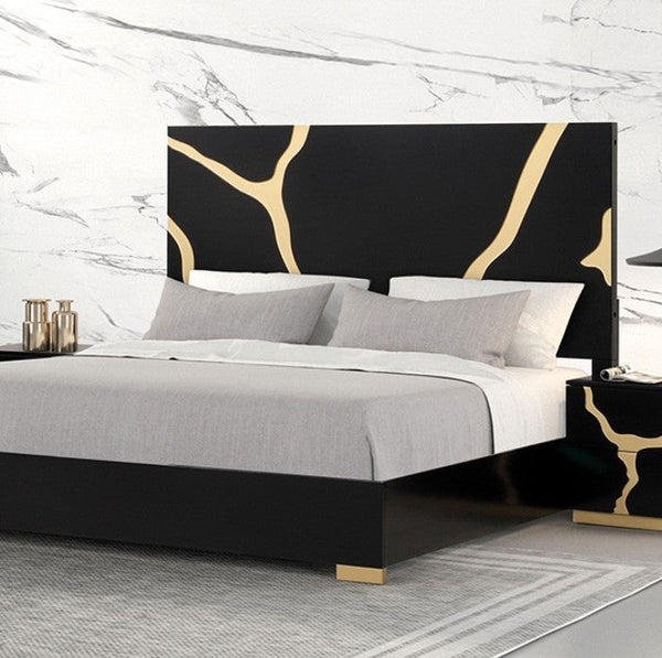 Primeberg Modern Black Gold Pattern Bed A modern bed frame with a black headboard and footboard featuring gold abstract branch-like patterns, styled with gray and white bedding. The bed is set against a white marble-patterned wall, with a matching black and gold nightstand on the right.