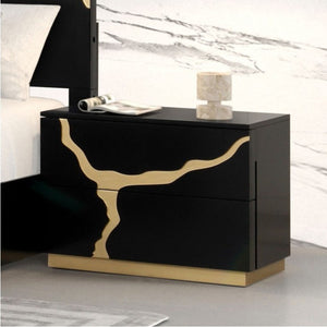 Primeberg Modern Black Gold Pattern Nightstand A modern two-drawer nightstand in glossy black with a bold gold abstract branch-like inlay and a gold base, shown beside a bed in a styled bedroom setting.