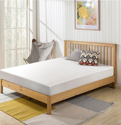 Primenite Memory Foam Mattress 6" A light natural wood bed frame with a white mattress, styled in a bright bedroom with a patterned accent pillow, a gray chair, and a striped rug.