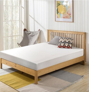 Primenite Memory Foam Mattress 6" A light natural wood bed frame with a white mattress, styled in a bright bedroom with a patterned accent pillow, a gray chair, and a striped rug.