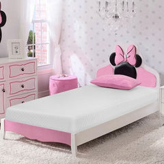 Primenite Memory Foam Mattress 12" A children's single bed styled in a pink and white bedroom, featuring a Minnie Mouse-inspired headboard with pink bow details, a white mattress, and a matching pink pillow. The room includes a pink dresser, a pink stool, and a window with sheer curtains.