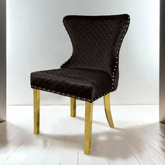 Primenova Upholstered Gold Black Dining Chair Black quilted chair with gold legs on a white floor and background