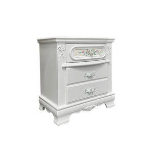 Primrose White Nightstand with Floral Accent A white two-drawer nightstand with ornate carved details, decorative drawer pulls, and a small floral accent panel on the top drawer, shown against a plain white background.