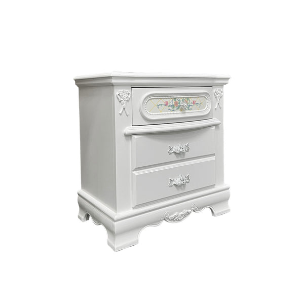 Primrose White Nightstand with Floral Accent A white two-drawer nightstand with ornate carved details, decorative drawer pulls, and a small floral accent panel on the top drawer, shown against a plain white background.