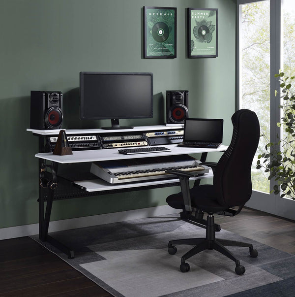Primtone Black White Music Production Desk A modern home studio setup featuring a black and white modular desk with audio equipment, a computer monitor, speakers, and a laptop, paired with a black office chair in a room with a green wall and window.