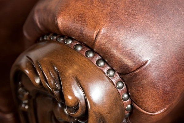 Prisya Traditional Leatherette Rolled Arm Sofa Close-up of a brown leather armchair with decorative nailhead trim