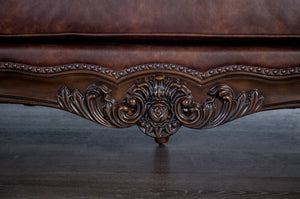 Close-up of a decorative brown leather sofa with intricate carvings.