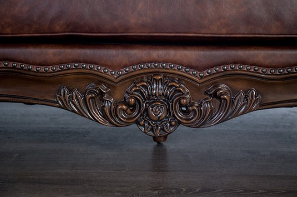 Close-up of a decorative brown leather sofa with intricate carvings.