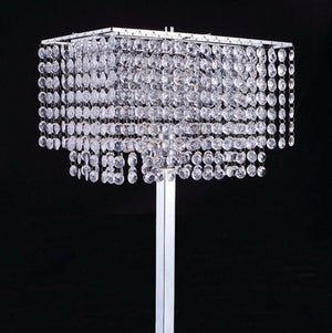 Remma Hanging Crystal Table Lamp A rectangular silver-toned chandelier-style table lamp covered in cascading clear crystal droplets, shown on a white stand against a black background.