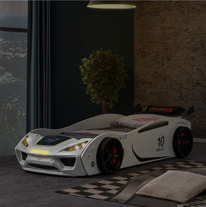 Rotvner Race Car-Bed With LED Headlights Children's race car bed in a dark room with a plant and window.
