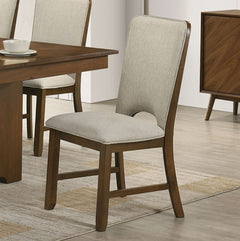 Saharia Mid-Century Modern Walnut Dining Chair A wooden dining chair with a light beige upholstered seat and back cushion, shown in a dining room setting next to a wooden table.