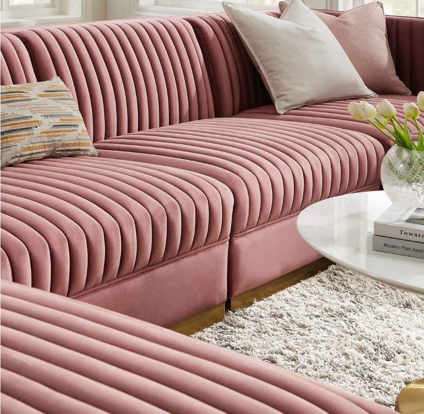 Sanchi 6PC Channel Tufted Velvet Modular Sectional Sofa Rose Pink sectional sofa in a living room with abstract art on the wall and a plant.