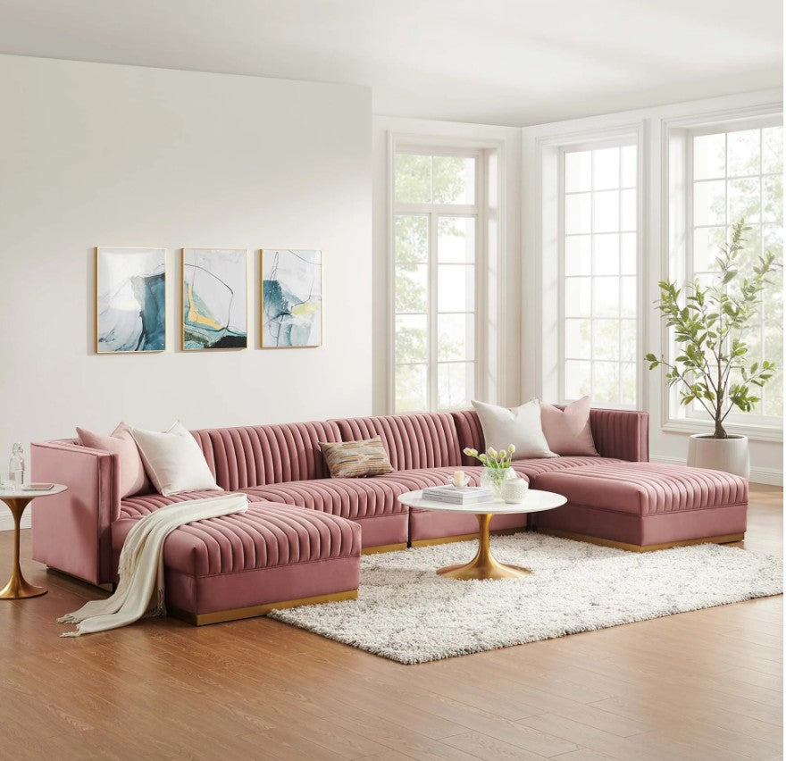 Sanchi 6PC Channel Tufted Velvet Modular Sectional Sofa Rose Pink sectional sofa in a living room with abstract art on the wall and a plant.
