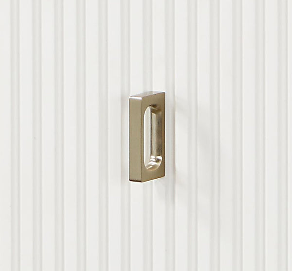 Serania Two Tone Chest A modern rectangular pull handle with a rounded rectangular bar and a central oval cutout, finished in brushed gold metal, mounted on a white vertically ribbed surface.