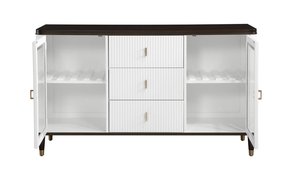 Serania Two Tone Dining Server A modern white sideboard cabinet with a dark brown top, glass-front doors on both sides, and three ribbed center drawers with small gold handles, shown against a light gray wall and wood floor.