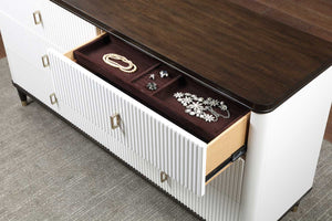 Serania Two Tone Dresser A close-up of a modern white ribbed dresser or console table with a dark wood top, showing an open drawer containing jewelry organizers and jewelry pieces.