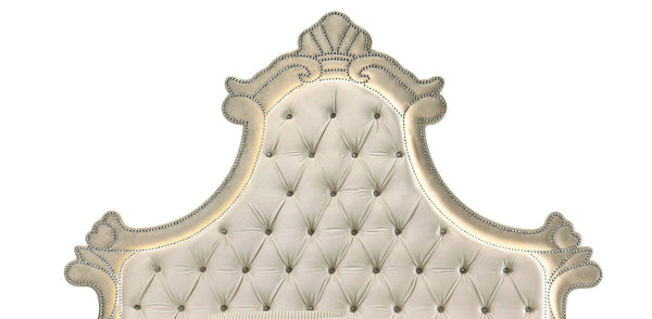 Sonya Beige Velvet Upholstered Traditional Style Bed An ornate tufted headboard with carved scrollwork and nailhead trim, shown against a plain white background.